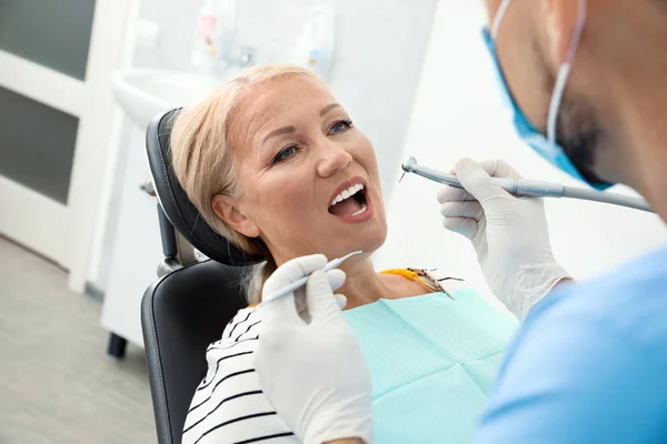 Odontólogo profesional que trabaja con paciente en clínica — Foto de Stock