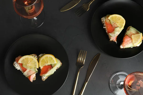 Composición plana con deliciosos bruschettas con salmón sobre mesa negra — Foto de Stock