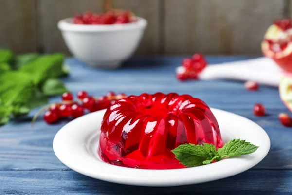 Délicieuse gelée rouge fraîche à la menthe sur table en bois bleu — Photo