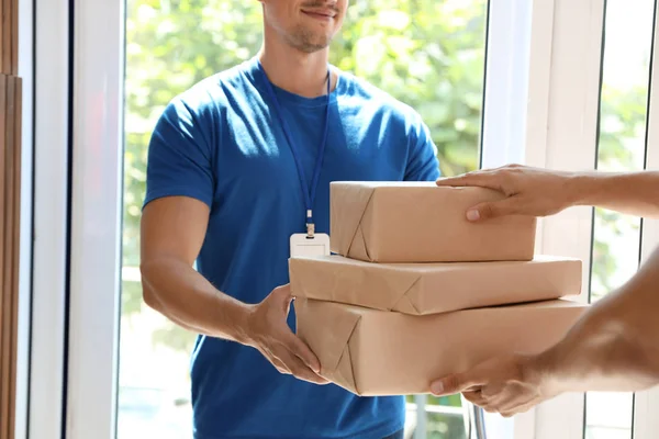 Young courier ger paket till klienten i dörröppningen, närbild — Stockfoto