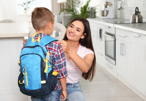 Mãe feliz e criança pequena com mochila pronta para a escola na cozinha — Fotografia de Stock