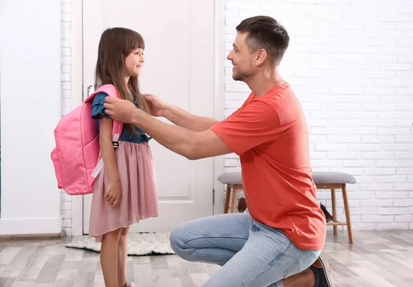 Pai feliz ajudando seu filho a colocar no saco da escola em casa — Fotografia de Stock