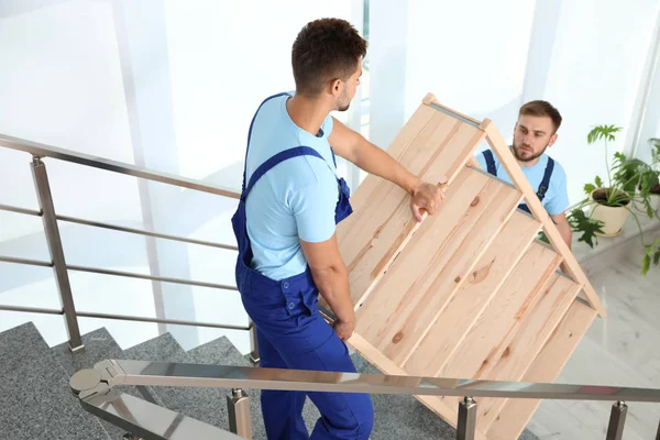 Professionella arbetare som transporterar trä rack på trappor i kontor. Flyttservice — Stockfoto