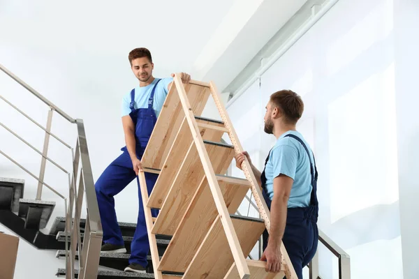 Trabajadores profesionales que llevan estante de madera en las escaleras de la oficina. Servicio móvil — Foto de Stock