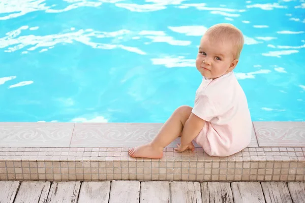 Pequeño bebé sentado cerca de la piscina al aire libre. Situación peligrosa — Foto de Stock