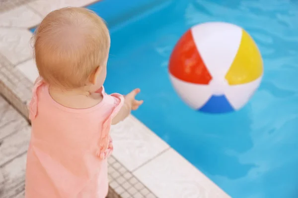 Małe dziecko sięgając do dmuchane piłkę na odkrytym basenie. Niebezpieczna sytuacja — Zdjęcie stockowe