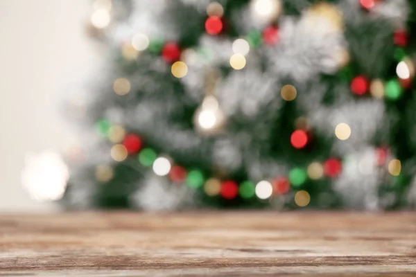 Leerer Holztisch und verschwommener Tannenbaum mit Weihnachtsbeleuchtung im Hintergrund, Bokeh-Effekt. Raum für Gestaltung — Stockfoto