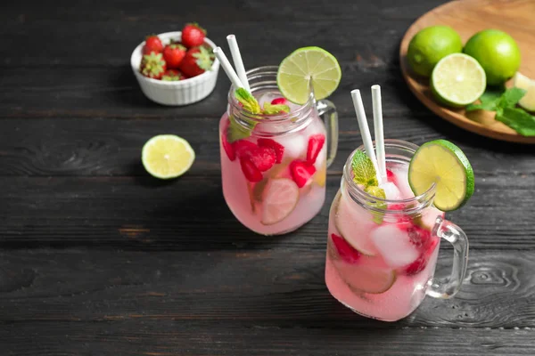 Mason jars with delicious refreshing drink on black wooden table — Stock Photo, Image