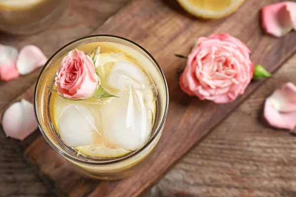 Deliciosa bebida refrescante con limón y rosa en la mesa de madera, vista superior —  Fotos de Stock