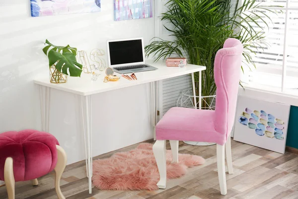 Stylish home workplace with elegant pink chair near window. Interior design