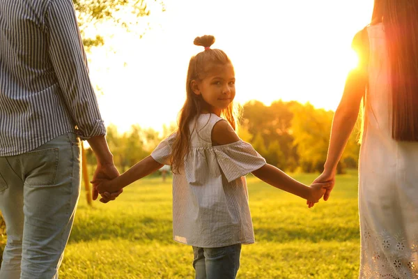 Holčička a její rodiče se drželi za ruce v parku. Šťastná rodina — Stock fotografie