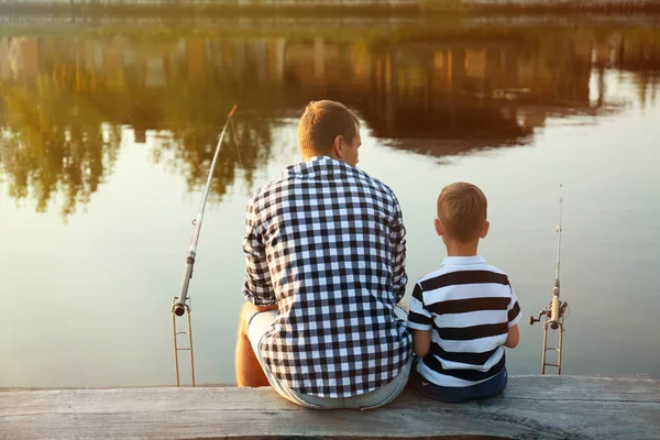 Dad and son fishing together on sunny day