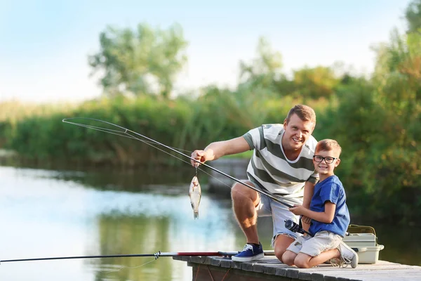 Pai e filho pesca juntos no dia ensolarado — Fotografia de Stock