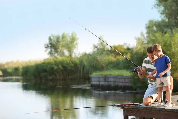 Dad and son fishing together on sunny day