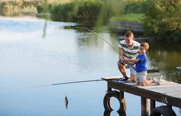 Pai e filho pesca juntos no dia ensolarado — Fotografia de Stock