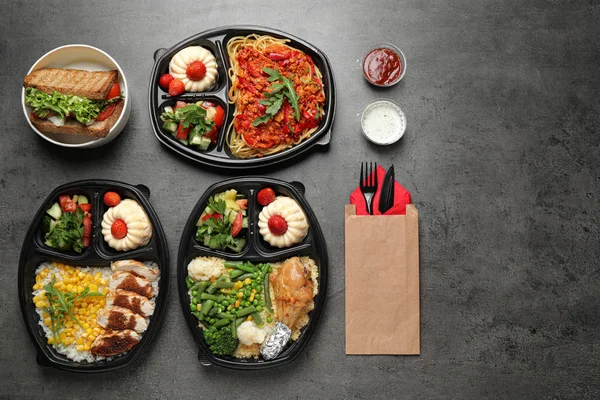 Lancheiras com diferentes refeições em mesa cinza, flat lay. Entrega de alimentos saudáveis — Fotografia de Stock