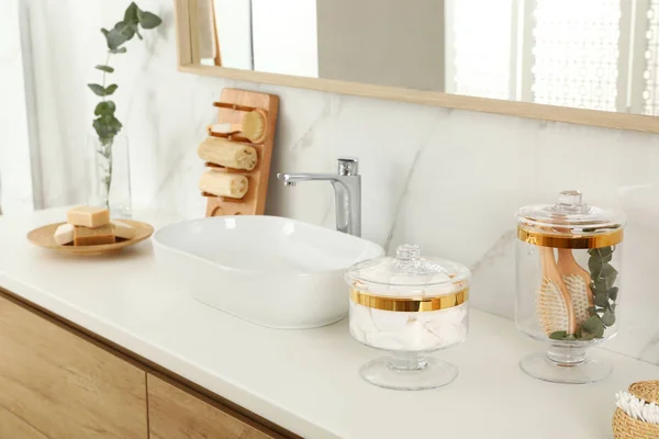 Vasi con batuffoli di cotone e spazzole per capelli sul piano del bagno — Foto Stock