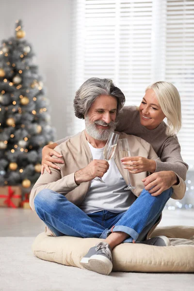 Feliz casal maduro com copos de champanhe celebrando o Natal em casa — Fotografia de Stock