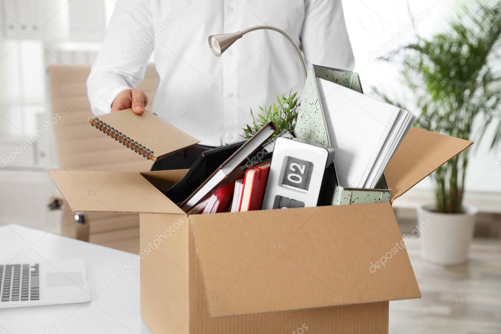 Young man packing stuff in box at office, closeup