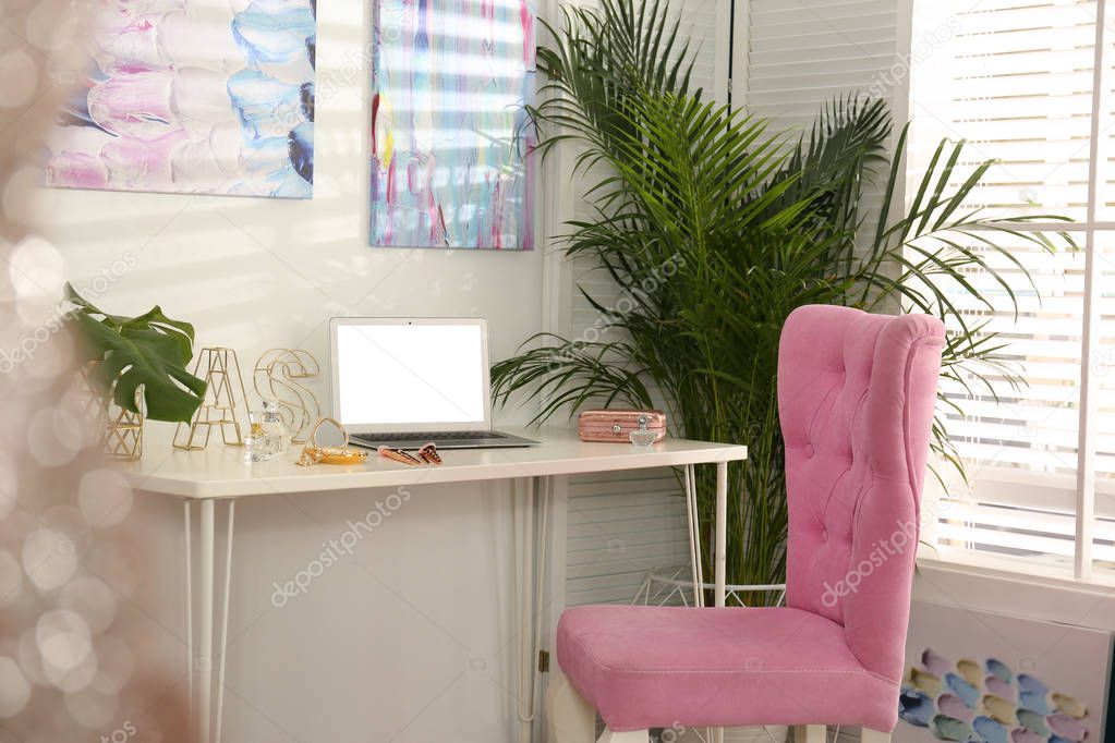 Stylish home workplace with elegant pink chair near window. Interior design