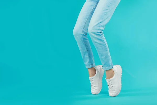 Woman in stylish sport shoes on light blue background. Space for text