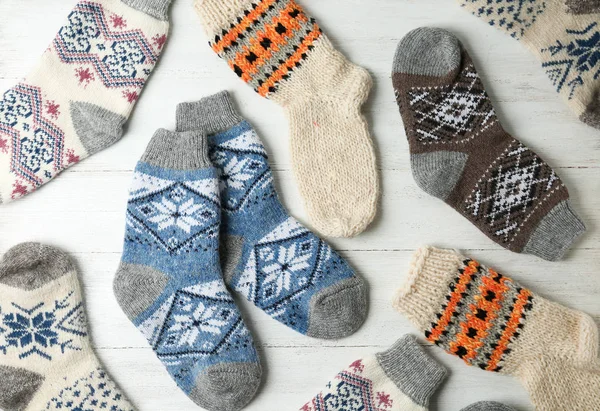 Different knitted socks on white wooden background, flat lay — Stock Photo, Image