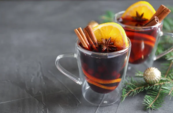 Copos de vidro com vinho quente e ramos de abeto na mesa cinza. Espaço para texto — Fotografia de Stock