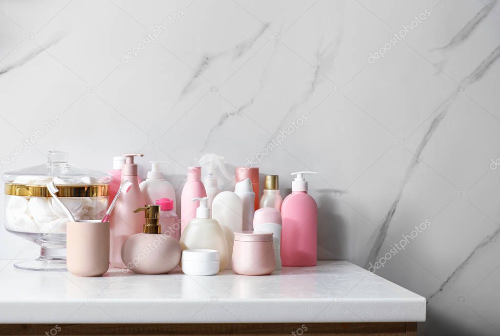 Stick deodorant and different toiletry on marble table near light wall, space for text