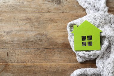 Ahşap arka plan üzerinde Ev modeli ve eşarp, metin için alan ile üst görünüm. Isıtma verimliliği