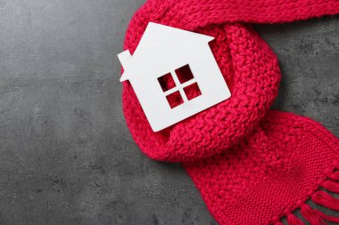 Ahşap ev modeli ve gri taş arka plan üzerinde kırmızı eşarp, üst görünümü. Isıtma verimliliği