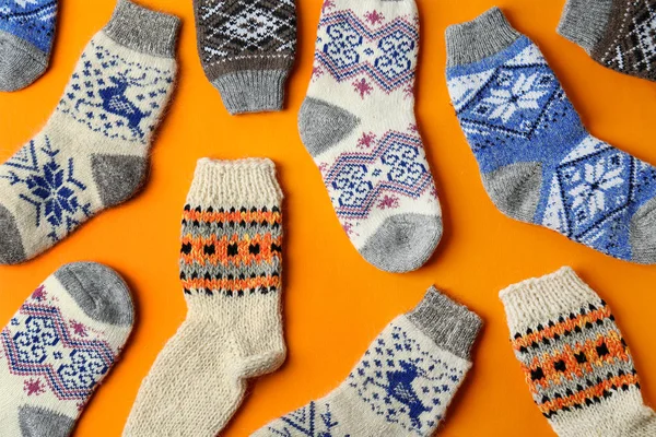 Verschiedene gestrickte Socken auf orangefarbenem Hintergrund, flach liegend. Winterkleidung — Stockfoto