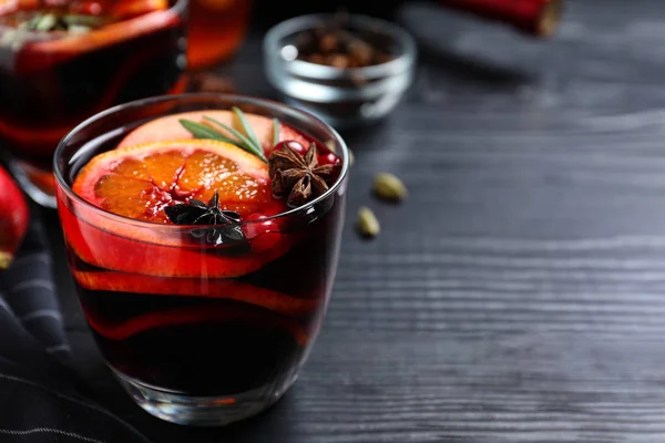 Cup of tasty mulled wine on black wooden table. Space for text — Stock Photo, Image
