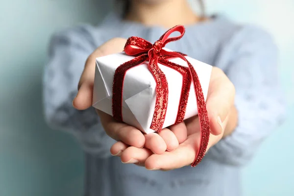 Frau hält schönes Weihnachtsgeschenk auf hellblauem Hintergrund, Nahaufnahme — Stockfoto