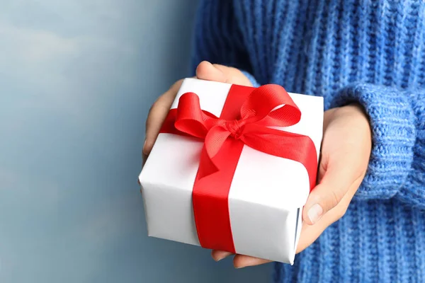 Jonge vrouw Holding kerstcadeau op blauwe achtergrond, close-up — Stockfoto