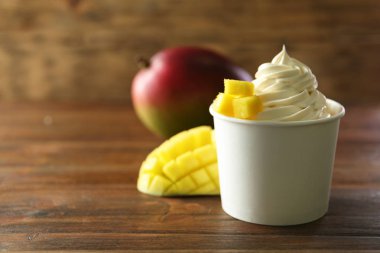 Ahşap masada mango ile lezzetli dondurulmuş yoğurt Fincan. Metin için alan