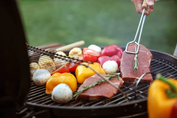 Homem cozinhar comida em churrasqueira ao ar livre, close-up — Fotografia de Stock