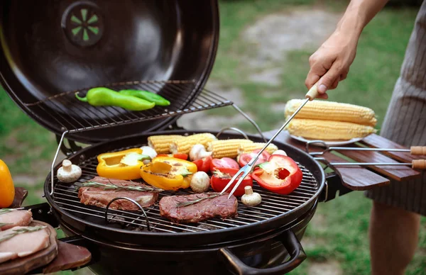 Hombre cocinando comida en la parrilla de barbacoa al aire libre, primer plano —  Fotos de Stock