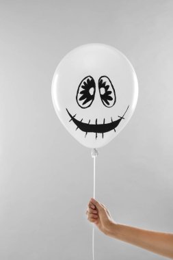Açık gri arka plan üzerinde Cadılar Bayramı partisi için ürkütücü balon tutan kadın, closeup
