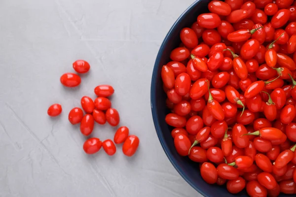 Tigela com bagas de goji frescas em fundo cinza, flat lay — Fotografia de Stock