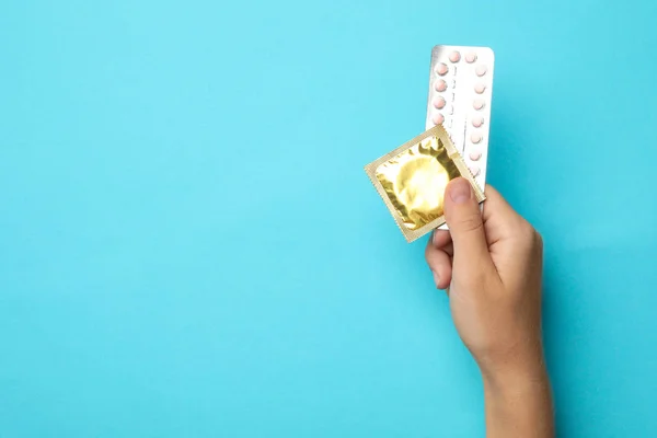 Femme tenant le préservatif et les pilules contraceptives sur fond bleu, vue du dessus avec espace pour le texte. Sexe sans risque — Photo