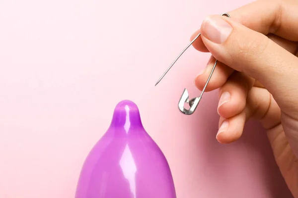 Donna piercing preservativo gonfiato con perno su sfondo rosa, primo piano. Sesso sicuro — Foto Stock
