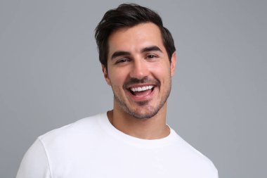 Gri arka plan üzerinde beyaz t-shirt yakışıklı genç adam Portresi