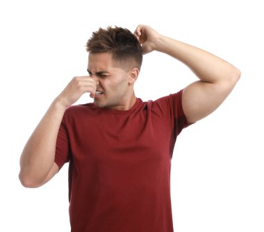 Beyaz arka plana karşı giysilerinde ter lekesi olan genç bir adam. Deodorant kullanma