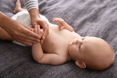 Battaniye üzerinde sevimli küçük bebek masaj genç kadın