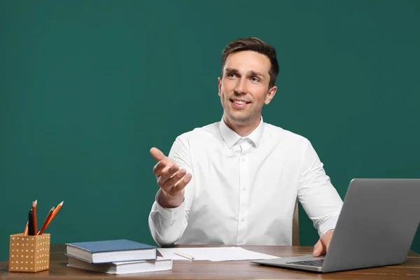 Porträt eines männlichen Lehrers am Tisch vor farbigem Hintergrund — Stockfoto