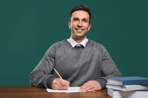 Porträt eines männlichen Lehrers am Tisch vor farbigem Hintergrund — Stockfoto