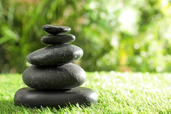 Stack of stones on green grass against blurred background, space for text. Zen concept — Stock Photo, Image