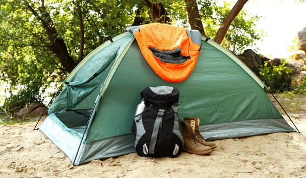 Camping tält med sovsäck, stövlar och ryggsäck på stranden — Stockfoto