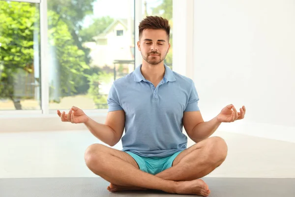 Guapo joven practicando yoga zen en interiores — Foto de Stock