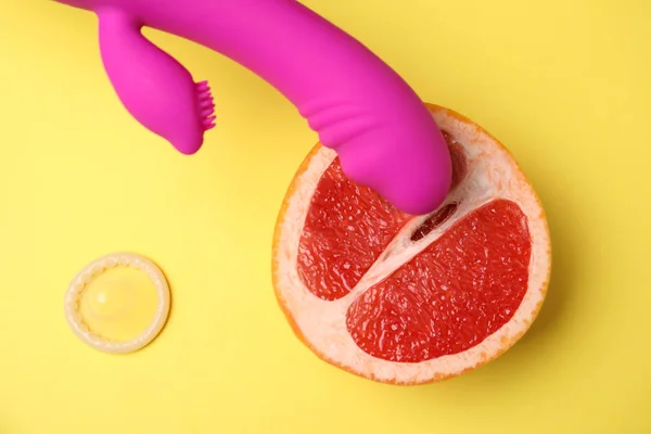 Hälfte Grapefruit, lila Vibrator und Kondom auf gelbem Hintergrund, flach liegend. Sexualkonzept — Stockfoto